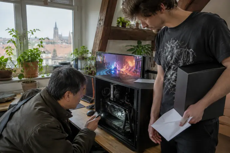 Lors d’une vente entre particuliers, un acheteur inspecte à la lampe le connecteur d’une carte graphique d’occasion qui tourne en charge chez le vendeur