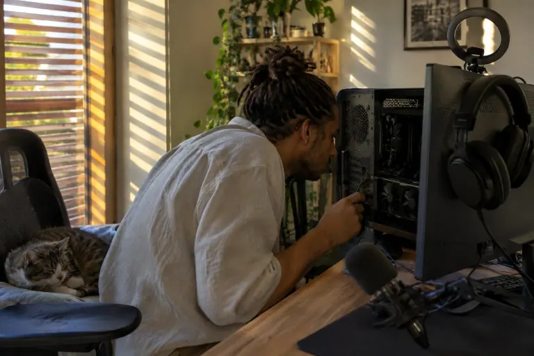 Dans son coin streaming à Montpellier, un jeune homme branche à tâtons un câble vidéo à l’arrière de sa carte graphique à deux ventilateurs