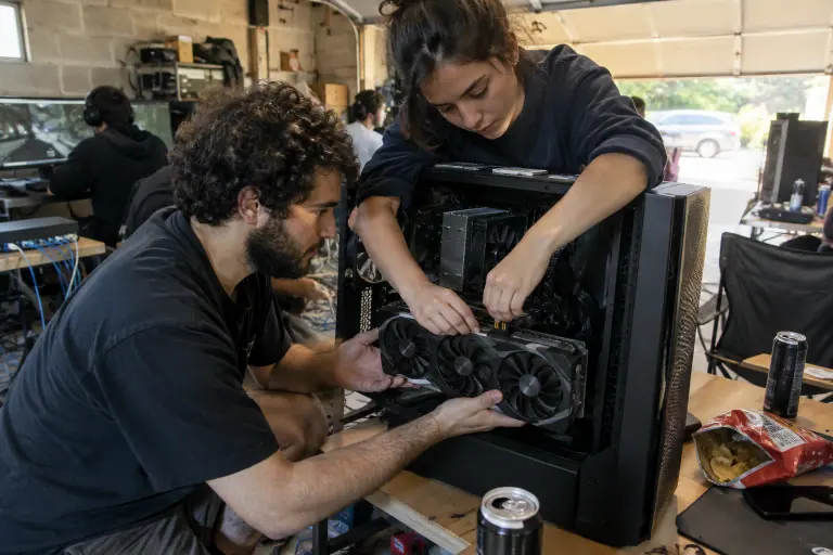 Pendant une LAN dans un garage, deux amis installent une grande carte graphique et branchent ses deux câbles d’alimentation 8 broches