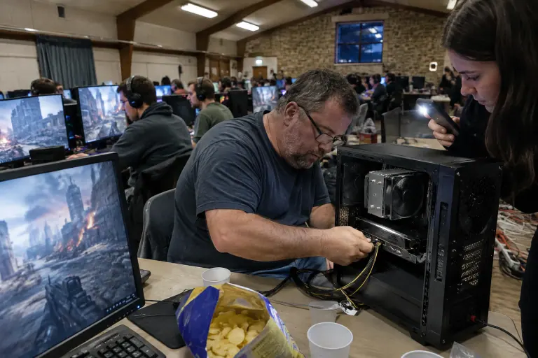 Lors d’une LAN dans une salle des fêtes de Normandie, un homme branche le câble d’alimentation de la carte graphique de son PC, entouré de joueurs