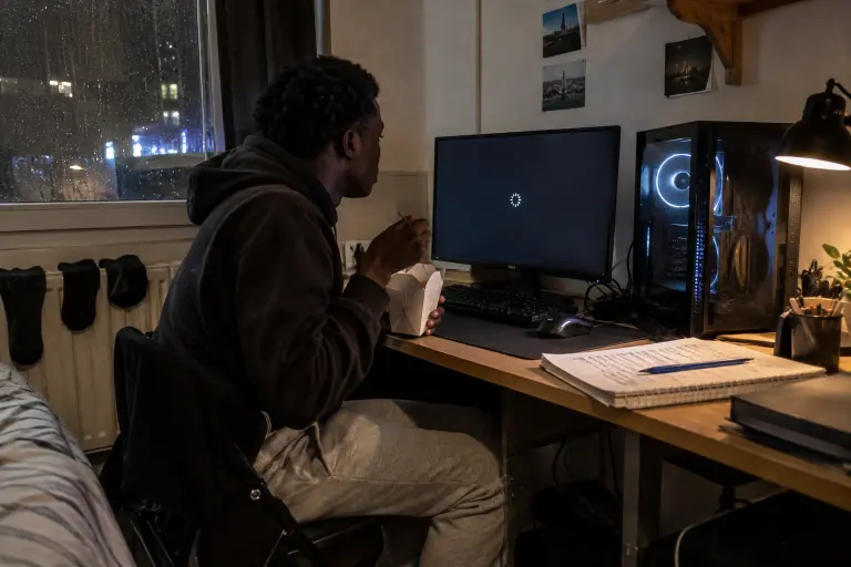 Dans sa chambre d’étudiant à Lille, un jeune homme mange des nouilles en attendant la fin de l’installation du pilote de sa carte graphique