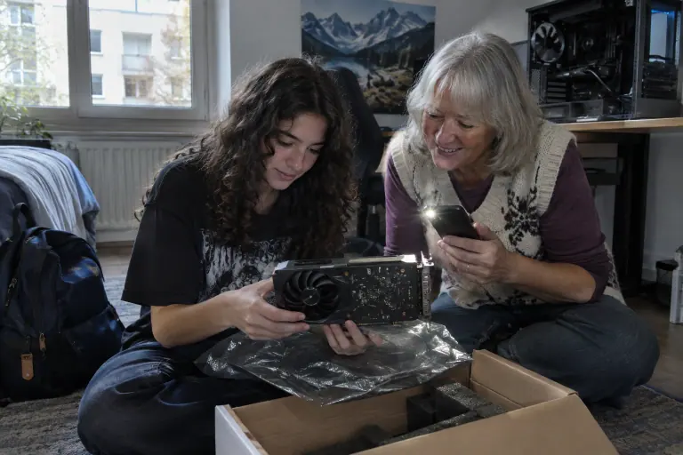 Dans une chambre à Metz, une adolescente et sa grand-mère déballent une carte graphique d’occasion à deux ventilateurs pour l’installer dans son PC