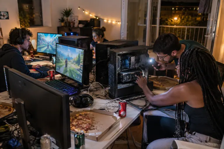 Pendant une LAN entre amis dans un salon, une jeune femme ouvre son PC pour montrer à un ami sa carte graphique compacte à deux ventilateurs