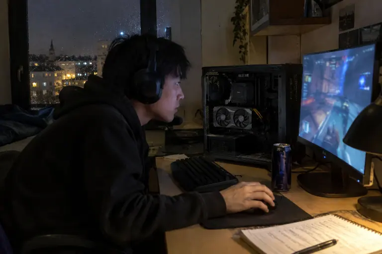 Tard le soir dans un studio étudiant à Rennes, un jeune joueur concentré sur une partie compétitive, à côté d’un petit PC ouvert équipé d’une carte compacte