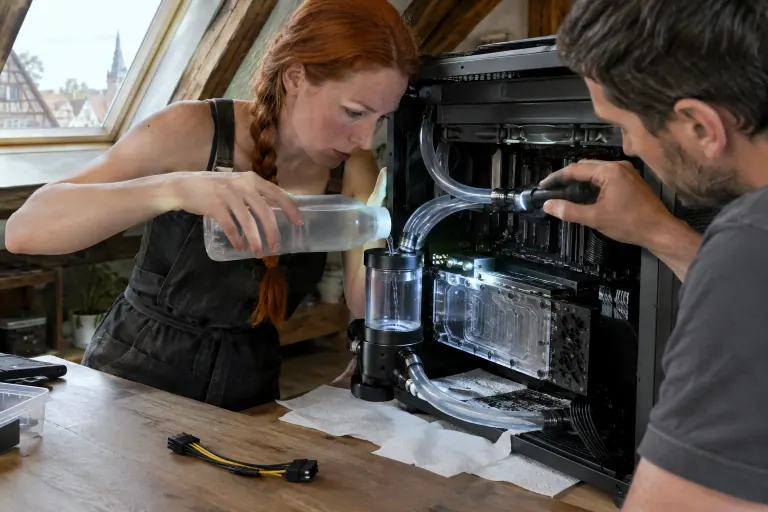Une femme remplit le réservoir d’une boucle de watercooling reliée à une carte graphique équipée d’un waterblock, des essuie-tout sous les raccords
